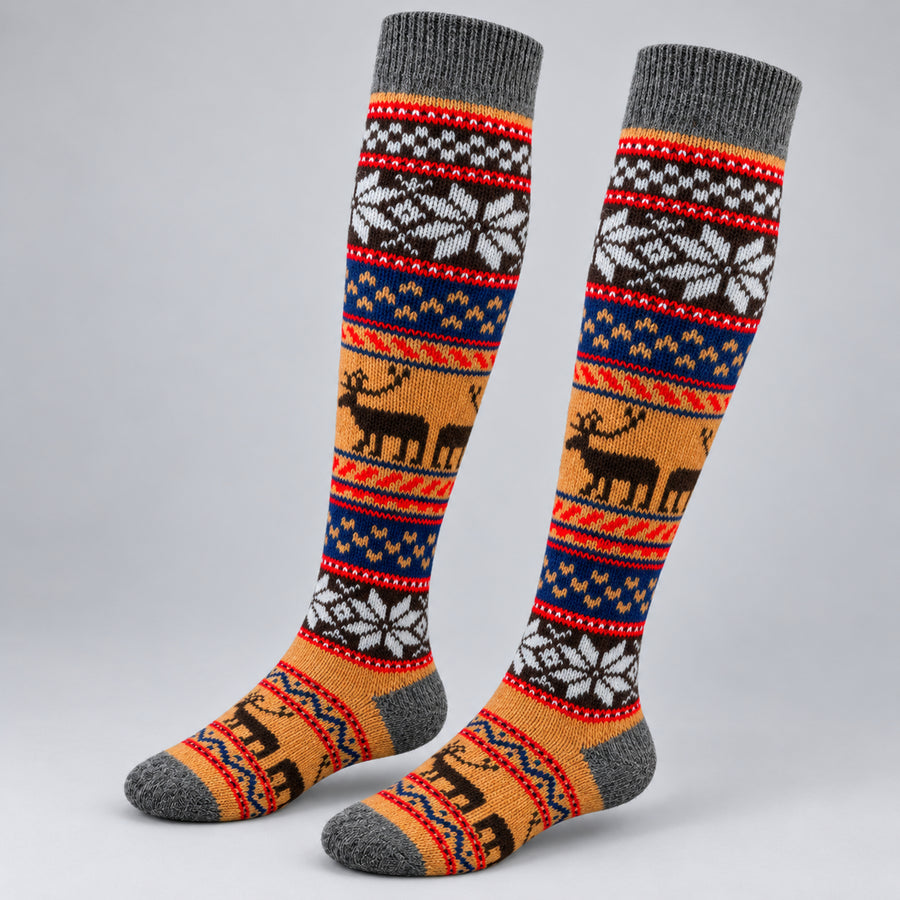 A pair of knee-high knit socks with a multicolor Nordic pattern featuring reindeer, snowflakes, and geometric stripes in orange, navy, red, white, and gray, displayed on a light gray background.