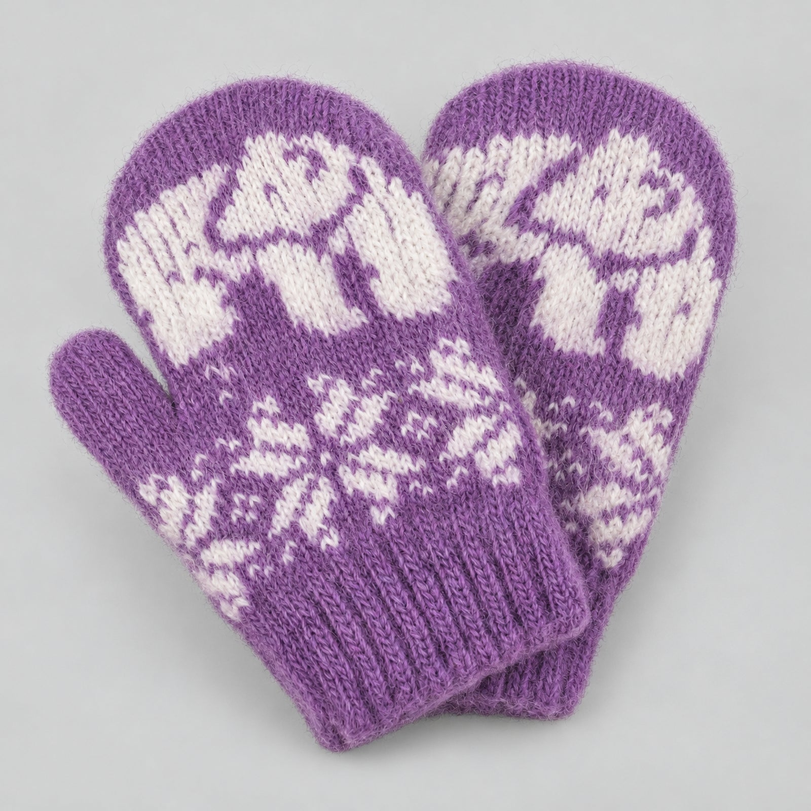 A pair of purple knit mittens with white fair isle patterns of polar bears and snowflakes, displayed on a neutral gray background.
