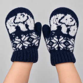A pair of navy blue knit mittens with white Fair Isle patterns, worn on hands against a light gray background.
