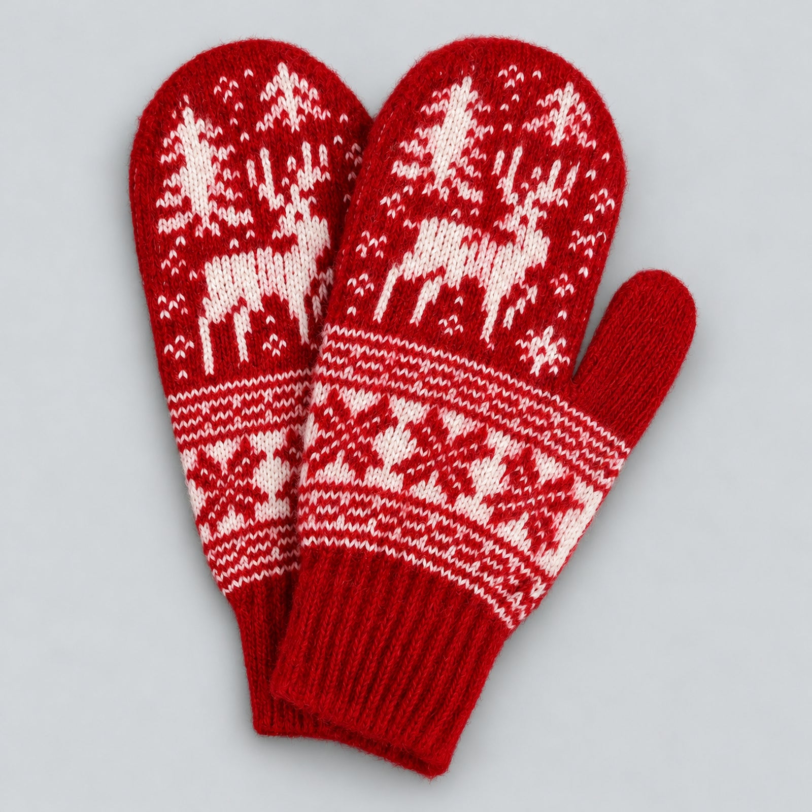 A pair of red knit winter mittens with white Nordic-style patterns featuring reindeer, snow trees, and snowflakes, displayed on a light gray background.