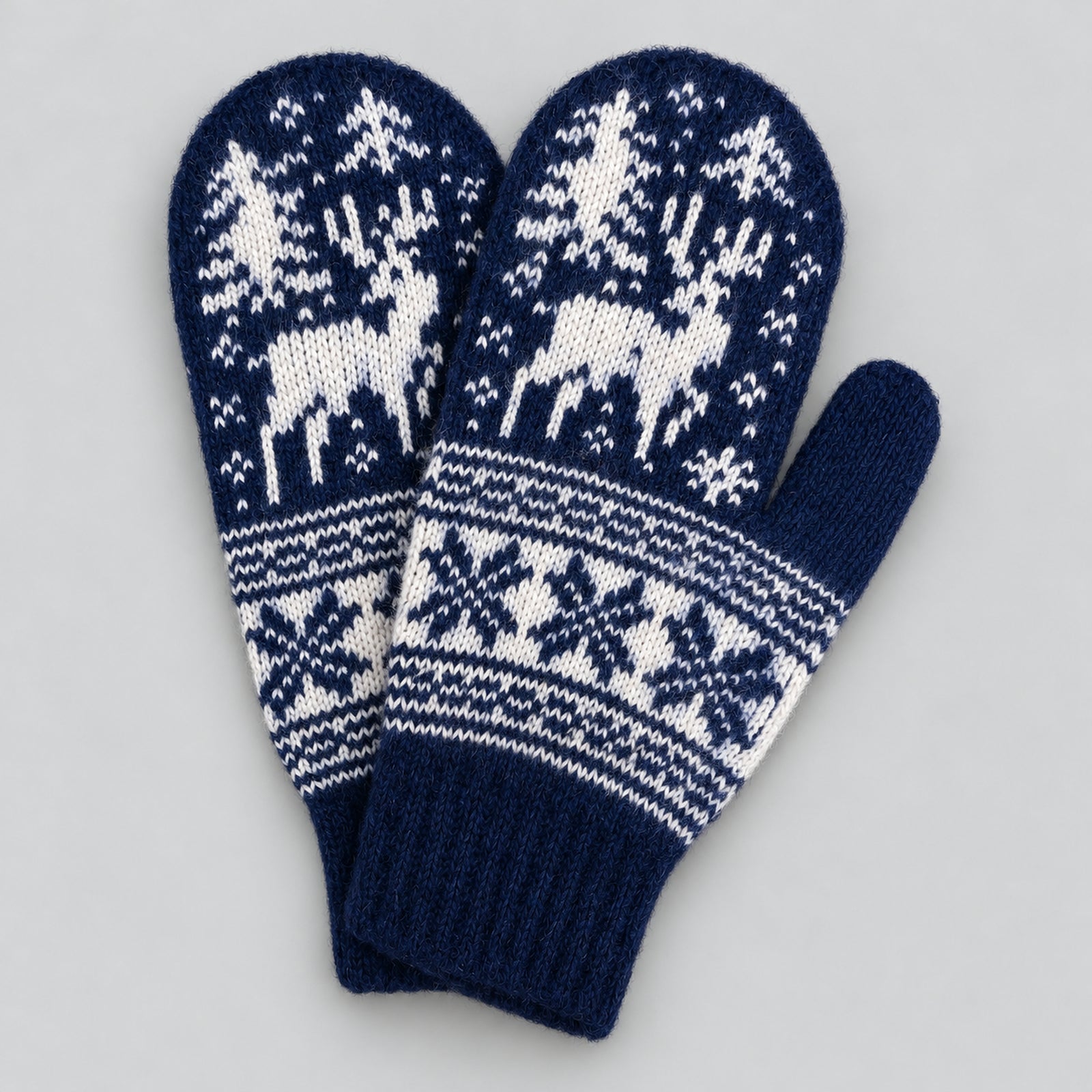 A pair of navy blue and white knit winter mittens featuring a Nordic pattern with reindeer, trees, and snowflakes, displayed on a neutral gray background.
