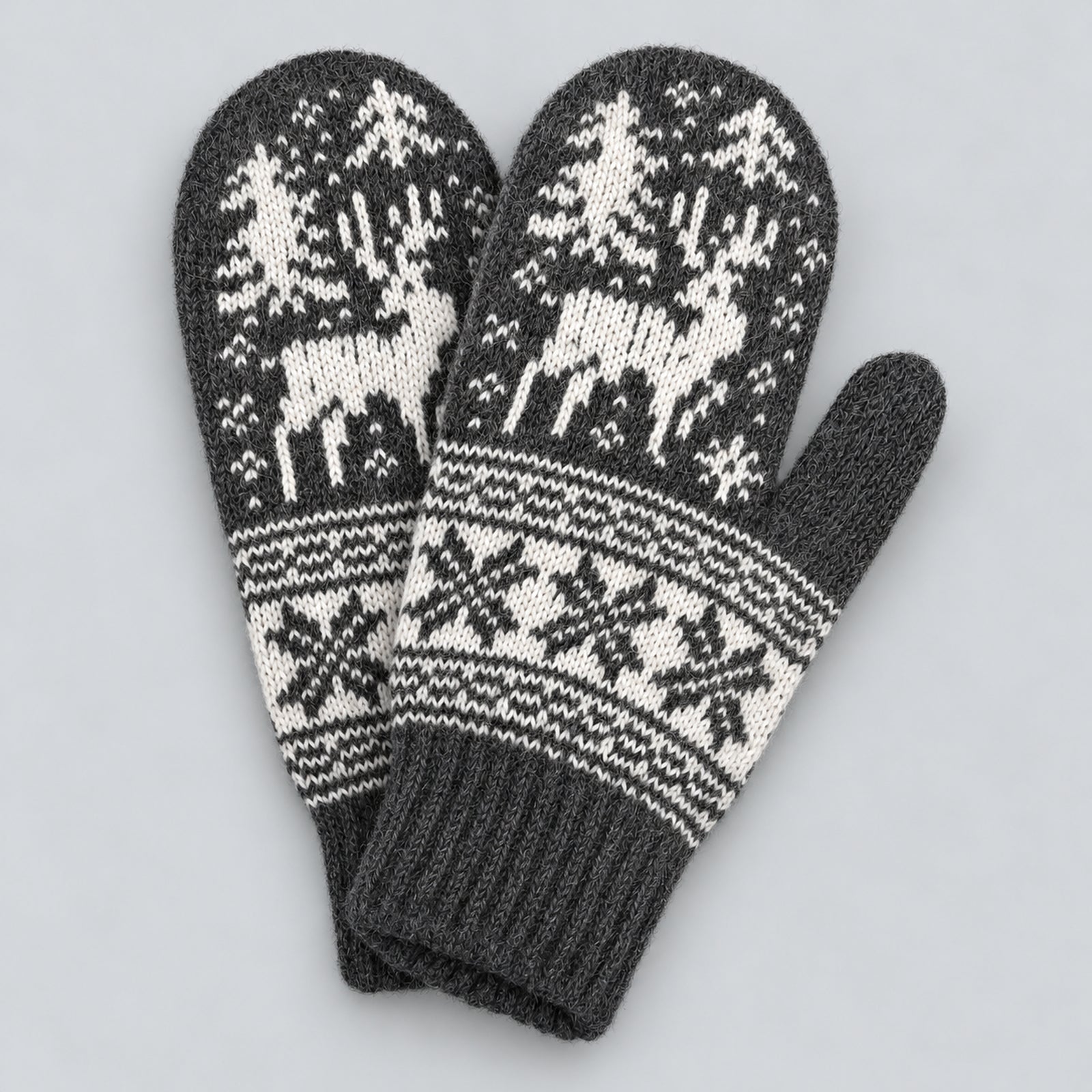 A pair of dark gray and off-white knit winter mittens featuring a Nordic design with reindeer, trees, and snowflakes, displayed on a neutral light gray background.