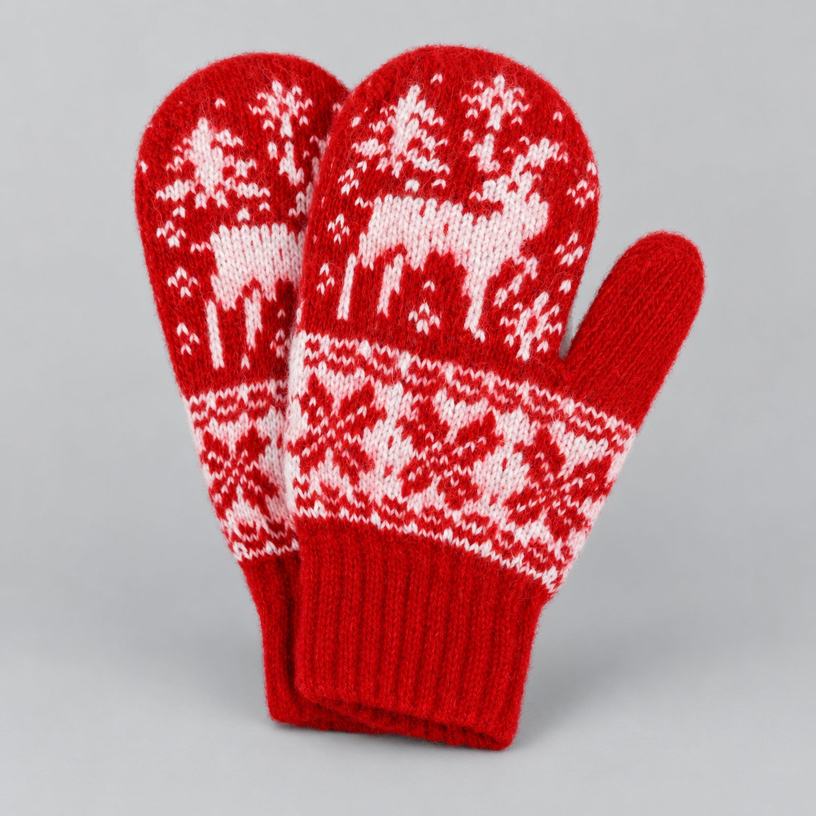 A pair of red knit winter mittens with white Nordic-style patterns, including reindeer and snowflakes, displayed on a neutral gray background.