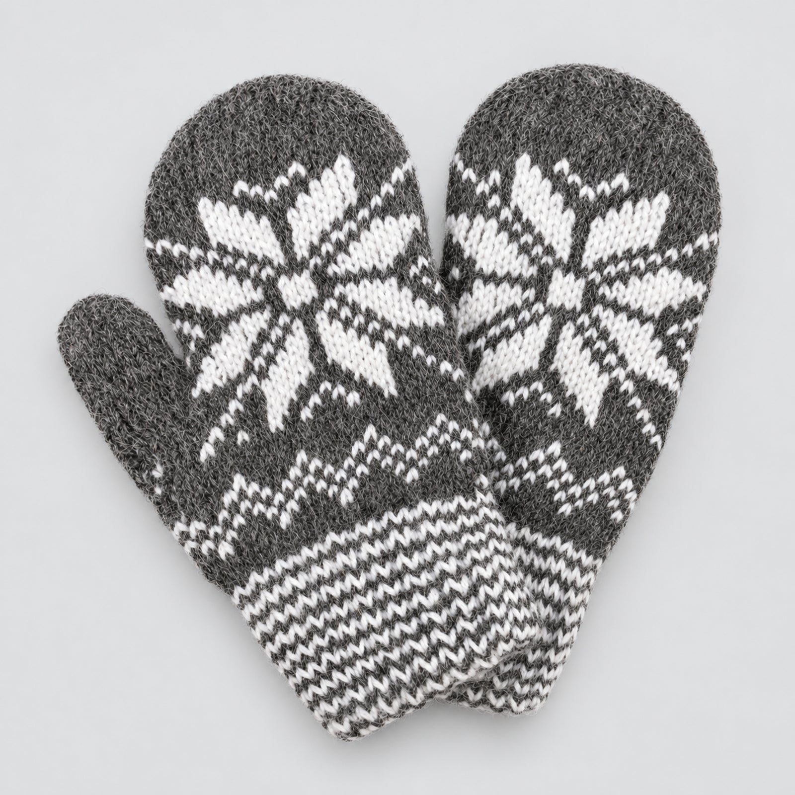 A pair of gray knit winter mittens with white snowflake and geometric patterns, displayed on a light gray background.