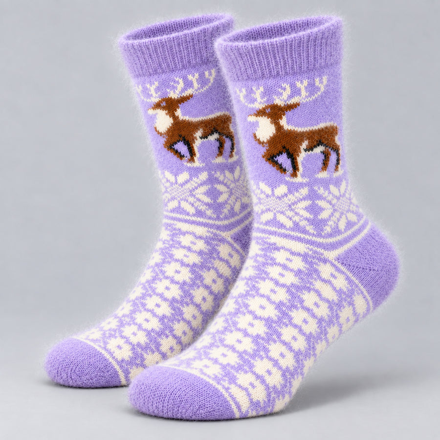 A pair of purple knit crew socks with a brown and cream reindeer design and white snowflake patterns, displayed on a neutral gray background.