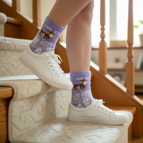 Person wearing white sneakers and purple socks with deer design on a staircase.