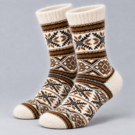 A pair of crew socks with a traditional Nordic or Fair Isle pattern in brown, cream, and black, displayed on a neutral gray background.