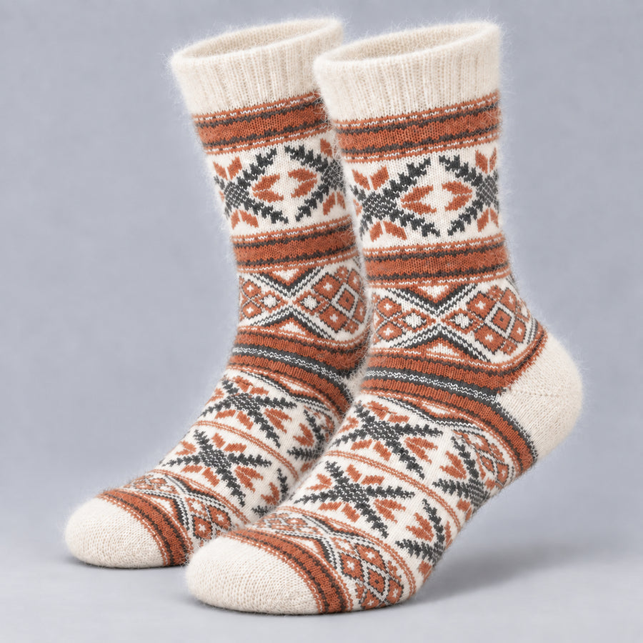 A pair of cream-colored knit socks with a brown, black, and gray geometric pattern, displayed against a neutral gray background.