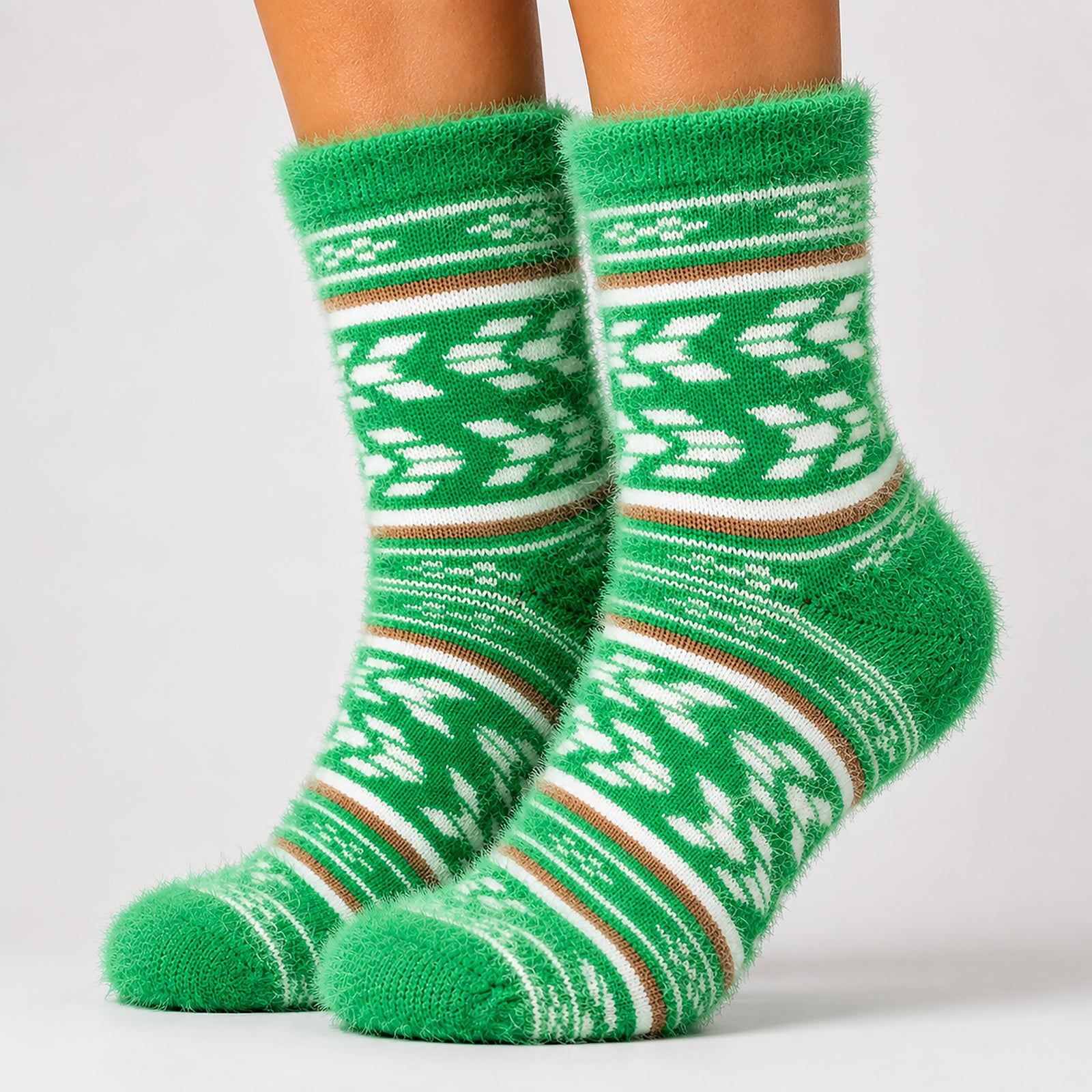 A pair of fuzzy green crew socks with white and brown Nordic/Fair Isle patterns, shown on a person's feet against a light gray studio background.