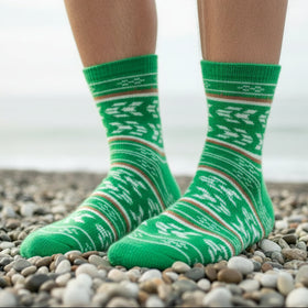 Green patterned socks on a person standing on pebbles with a blurred background