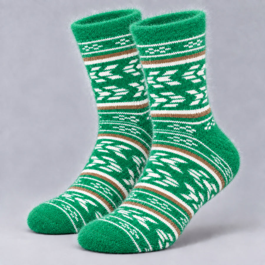 A pair of green fuzzy socks with white and brown Nordic/Fair Isle patterns, displayed on a neutral gray background.
