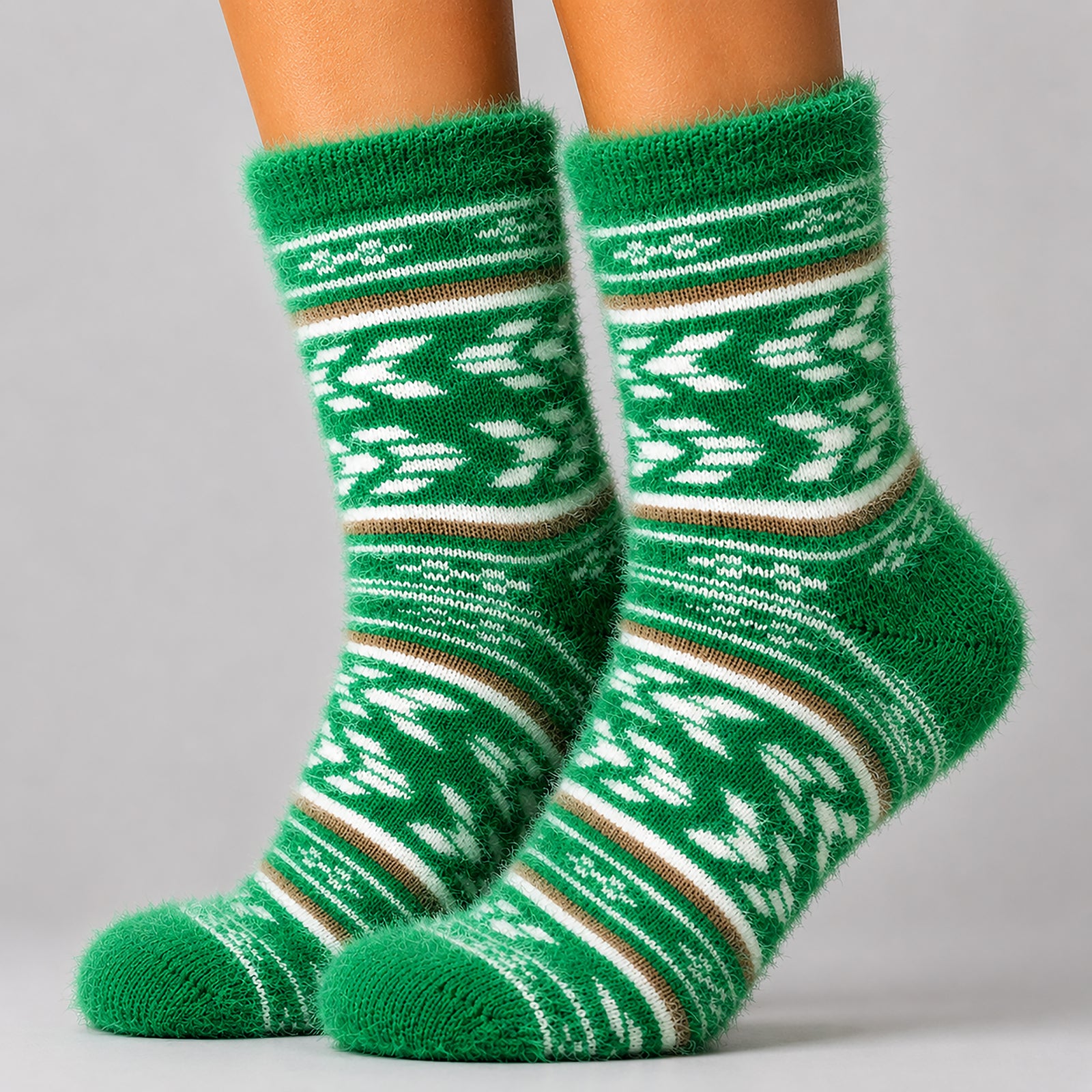 A pair of green fuzzy knit socks with white and brown Fair Isle style patterns, shown on a person's feet against a light gray background.