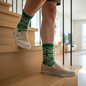 Person wearing green patterned socks and white sneakers on a staircase.