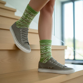 Person wearing green patterned socks and dark shoes on a staircase