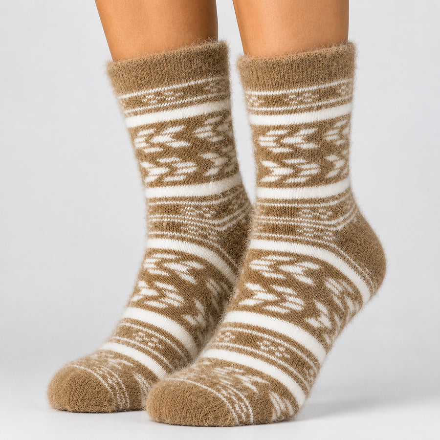 A pair of fuzzy ankle socks with a brown and cream fair isle pattern, shown on a model's feet against a light gray background.