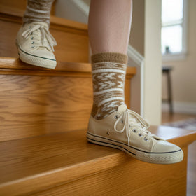 Person wearing beige sneakers and patterned socks on wooden stairs