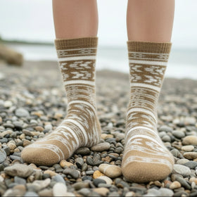Person wearing patterned socks standing on a pebbly beach