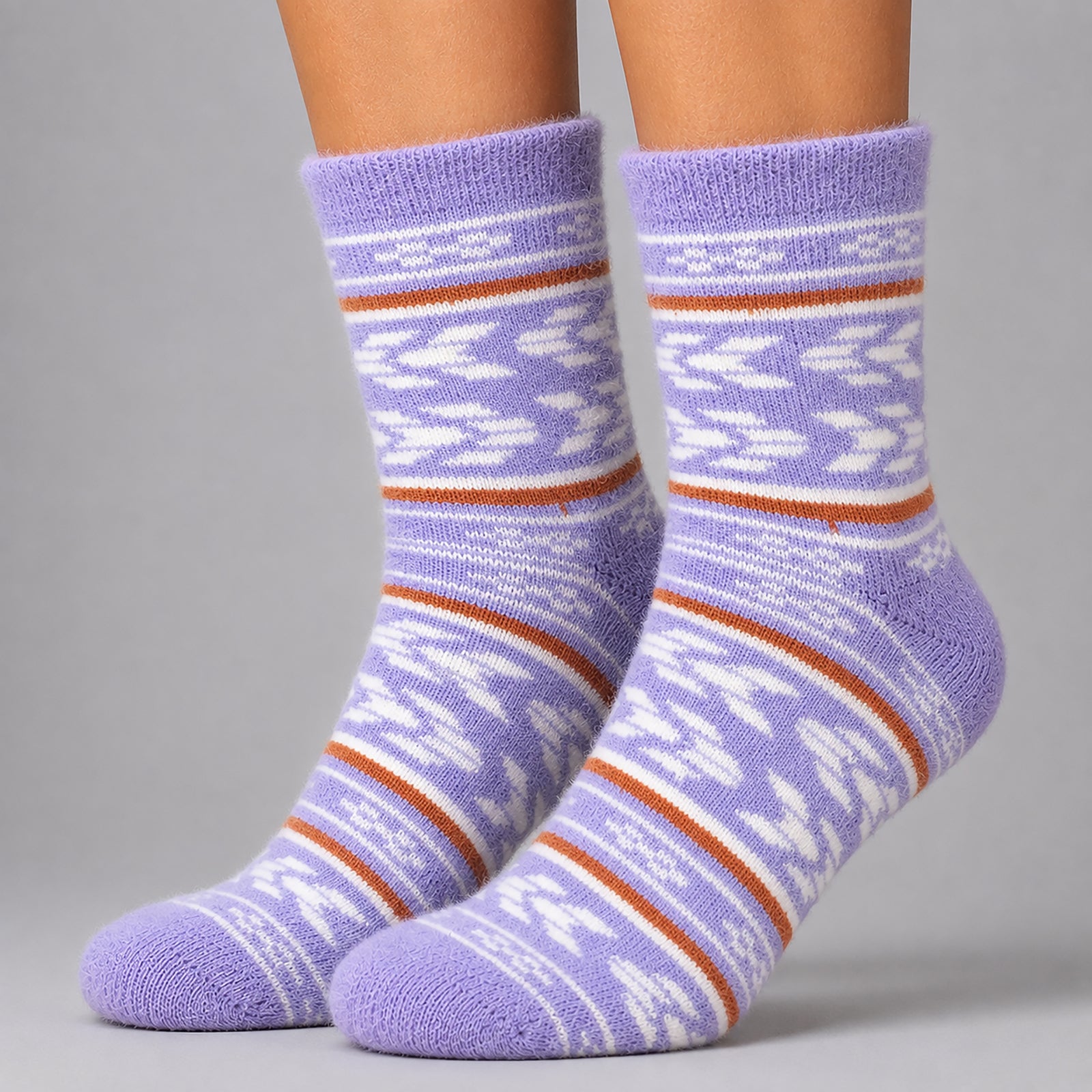 A pair of crew socks worn on feet, featuring a light purple base with white geometric patterns and thin rust-orange horizontal stripes, set against a solid gray background.