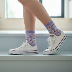 Person wearing white sneakers and patterned socks on a staircase.