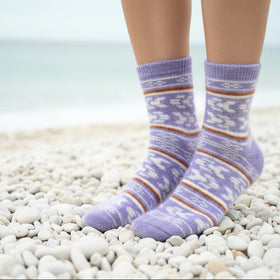 Purple patterned socks on a person standing on pebbles with a blurred background
