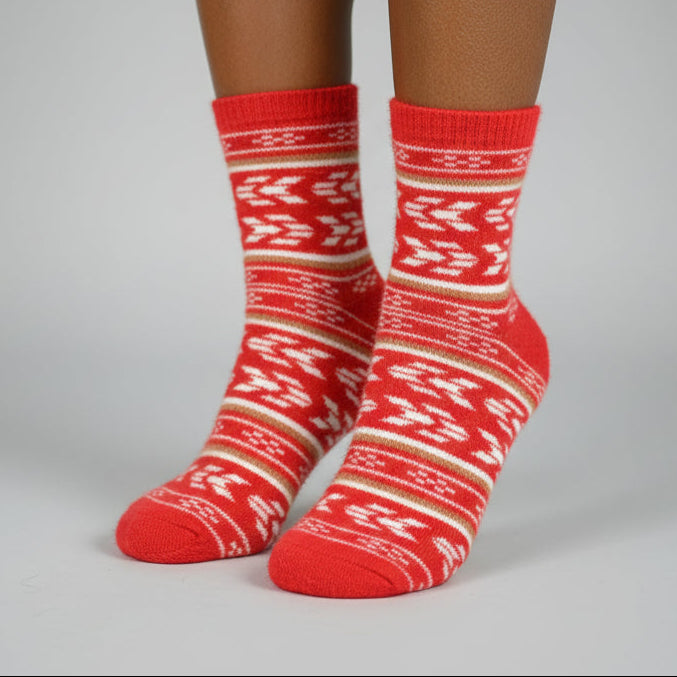 Red patterned sock on a foot, standing on a gray stool with a wooden chair in the background.