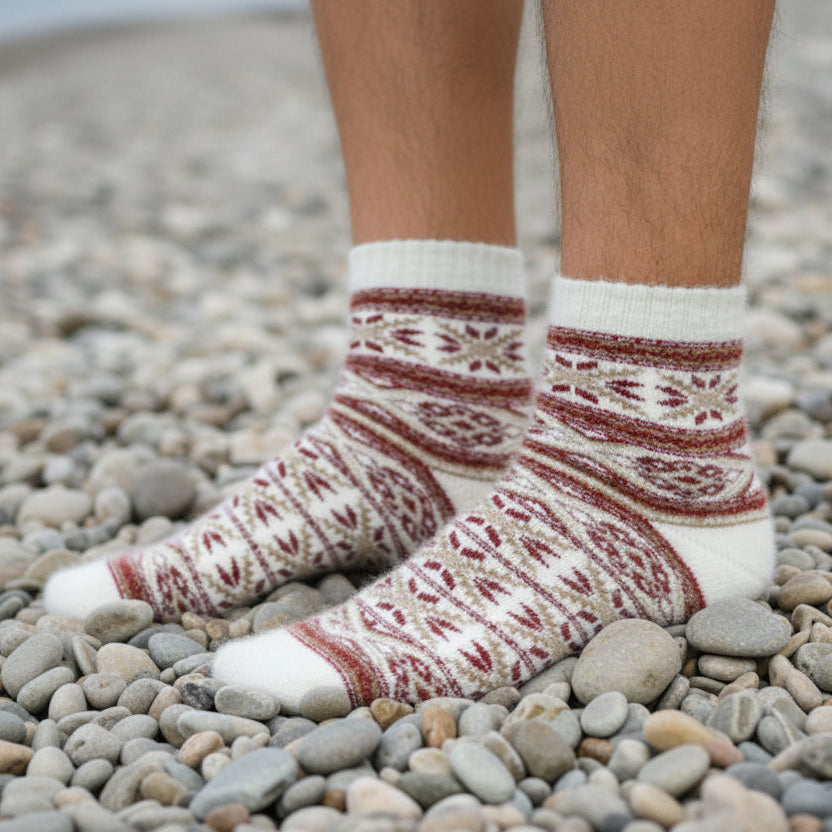Person wearing patterned socks on a pebbly beach