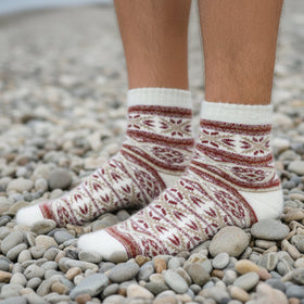 Person wearing patterned socks on a pebbly beach