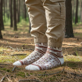 Person wearing patterned angora wool socks and beige pants standing in a forest
