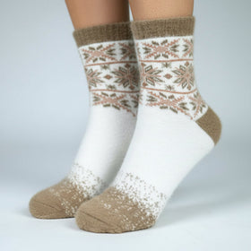 Pair of white socks with brown pattern worn on a plain background