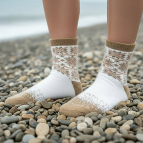 White socks with brown patterns worn on a pebbly beach