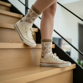 Person wearing white sneakers and patterned socks climbing wooden stairs.