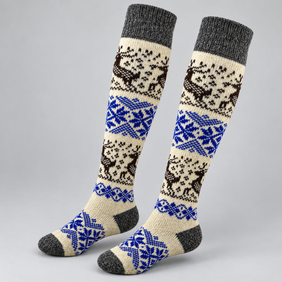 A pair of knee-high knit socks with a traditional Nordic pattern featuring brown reindeer, blue snowflakes, and cream and gray sections, displayed on a light gray background.
