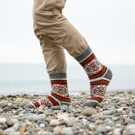 Person wearing patterned socks on a beach background