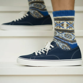 Blue and patterned sock on a person's foot with a blue shoes