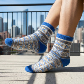Person wearing blue and gray patterned socks on a rooftop with city skyline in the background