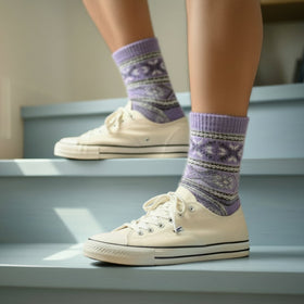 Person wearing white sneakers and purple patterned socks on a staircase
