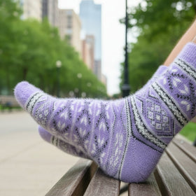 Person wearing purple patterned socks sitting on a bench with a cityscape background