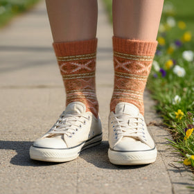 Person wearing white sneakers and patterned socks standing on a path with flowers.