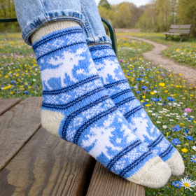 Blue and white patterned sock worn by a person sitting on a wooden bench in a field of flowers.
