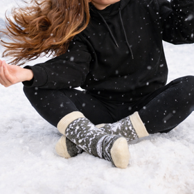 Person sitting in the snow wearing black hoodie and patterned socks
