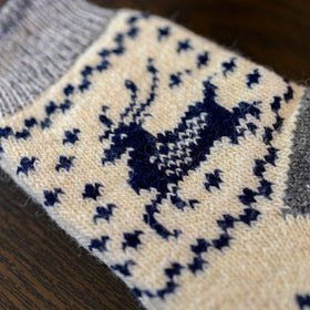Close-up of a sock with reindeer pattern on a wooden surface