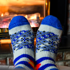 Pair of feet wearing blue and white patterned socks in front of a fireplace.