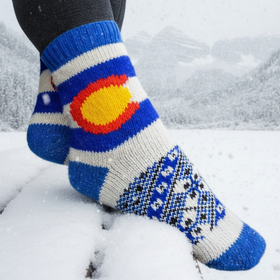 Colorful socks with a design resembling the Colorado flag in a snowy landscape