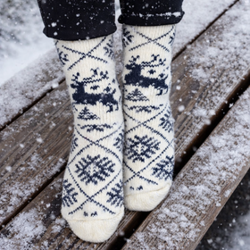 White socks with blue patterns worn on a wooden deck with snow.