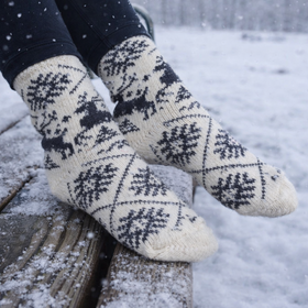 Person wearing patterned socks sitting on a snowy bench.