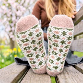 Person wearing patterned socks sitting on a wooden bench with a blurred natural background
