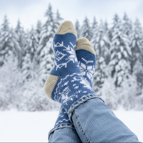 Blue knitted socks with white patterns worn outdoors in the winter.
