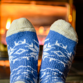 Blue patterned socks being worn with a warm fire in the background