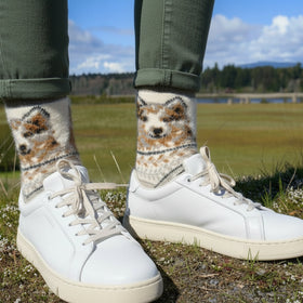 Person wearing dog-themed socks with beige sneakers in a natural setting.