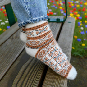 Person wearing a patterned sock on a wooden bench with a floral background